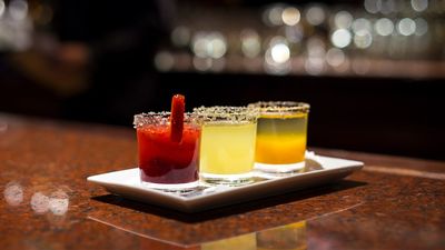 cocktail flight with red, yellow and orange colored drink