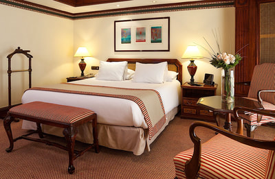 room with large bed, two nightstands and a seating bench at the foot of the bed 
