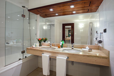 bathroom with double sink and shower with glass door